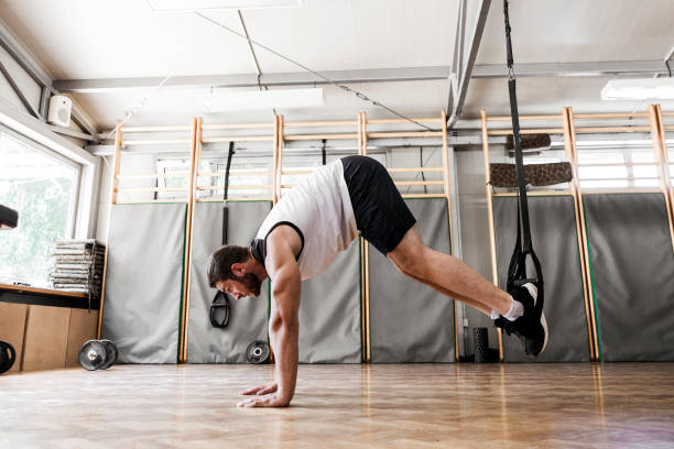 istock Young man workout in healthy club with straps 1018152118