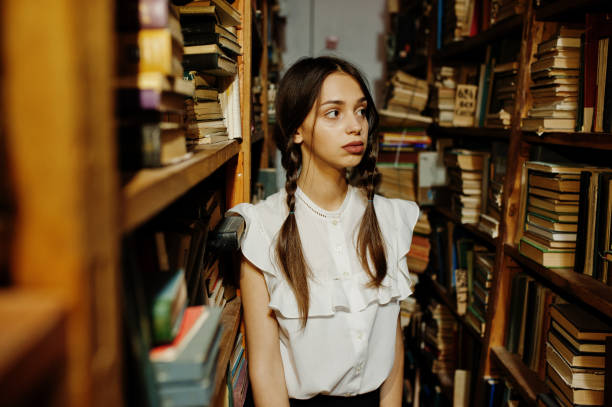 istock Girl with pigtails in white blouse at old library. 1018158642