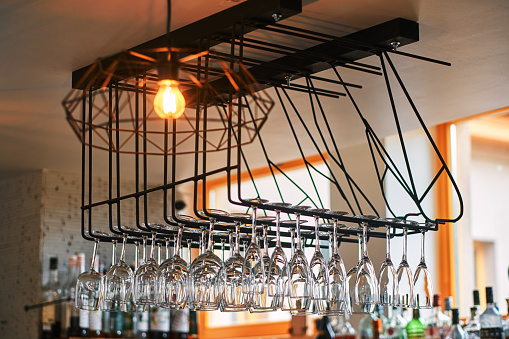 Close-up image of a wine glasses hanging in a bar above the bar counter.