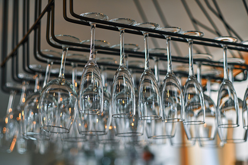 Close-up image of a wine glasses hanging in a bar above the bar counter.