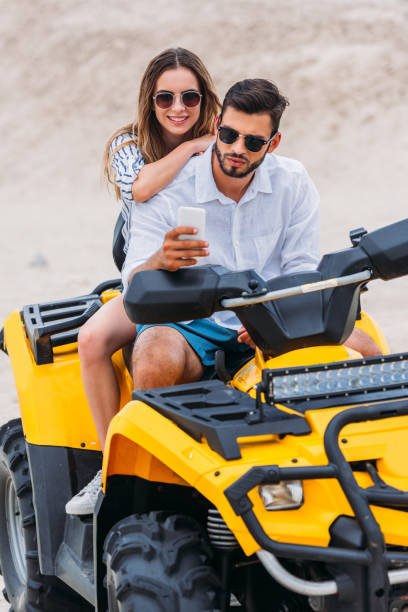 istock beautiful young couple taking selfie while sitting on ATV in desert 1018199258