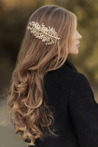 Photo of Hairstyle of long hair curly blonde with handmade gold hairpin