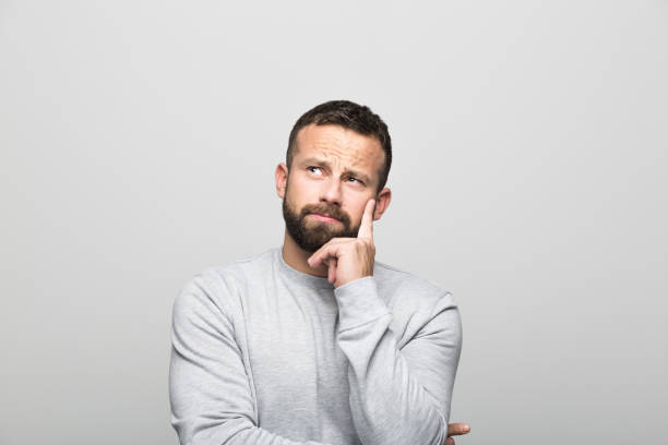 istock Portrait of pensive bearded young man, grey background 1018214946