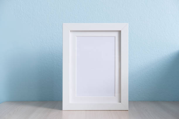 istock blank white picture frame on the table wood with blue background 1018221950