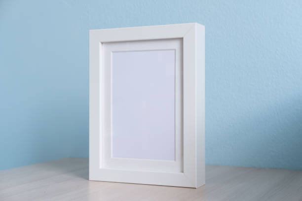 istock blank white picture frame on the table wood with blue background 1018222078