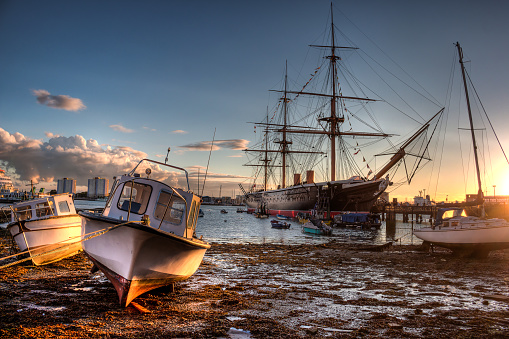 Portsmouth Harbour during sunset with boats and HMS Warrior in the background. HDR style image