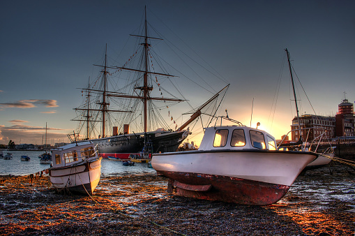 Portsmouth Harbour during sunset with boats and HMS Warrior in the background. HDR style image