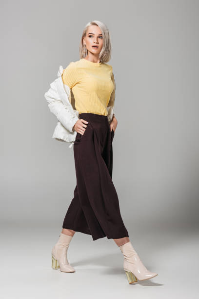 istock young female model in stylish outfit posing with hands in pockets on grey background 1018241946