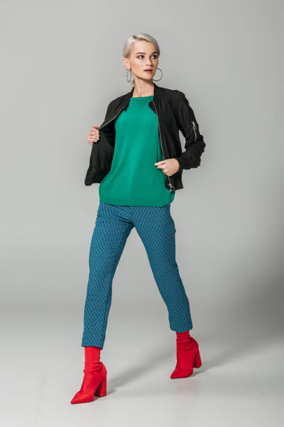 istock stylish female model in black jacket and red boots posing on grey background 1018242512