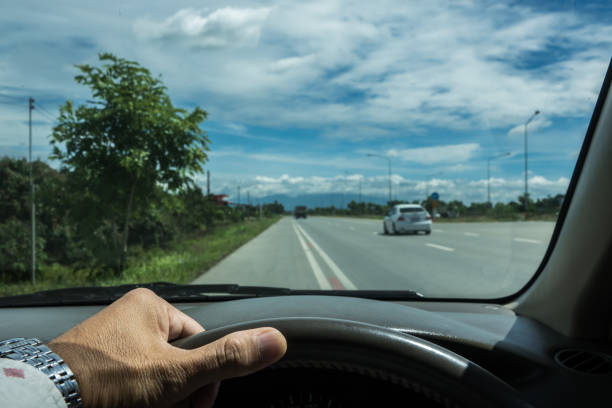 istock A hand holding steering wheel beside the road for safe drive 1018246420