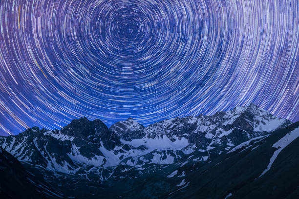 rotazione di tracce stellari nel cielo notturno sulle montagne con la neve - sciame meteorico geminidi immagine foto e immagini stock