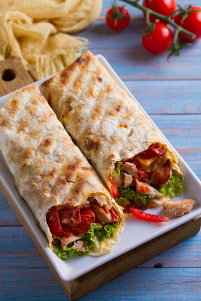 istock Chicken caesar salad wraps with bacon, tomatoes, lettuce and cheese. Tortilla, burritos, sandwiches twisted rolls 1018256814