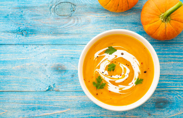 Pumpkin and carrot soup with parsley on blue background Top view.