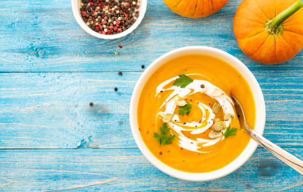 istock Pumpkin and carrot soup with parsley on blue background Top view. 1018260450