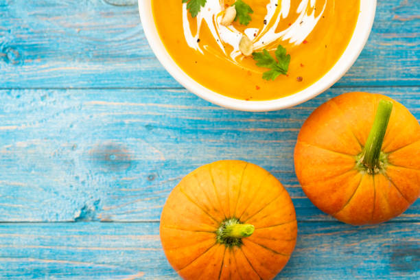 istock Pumpkin and carrot soup with parsley on blue background Top view. 1018260696