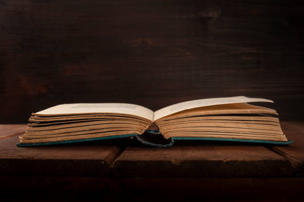 istock An open old book on a dark background with copy space 1018267504