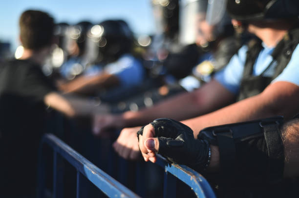 istock Police officer hands on a security fence during a riot 1018272786
