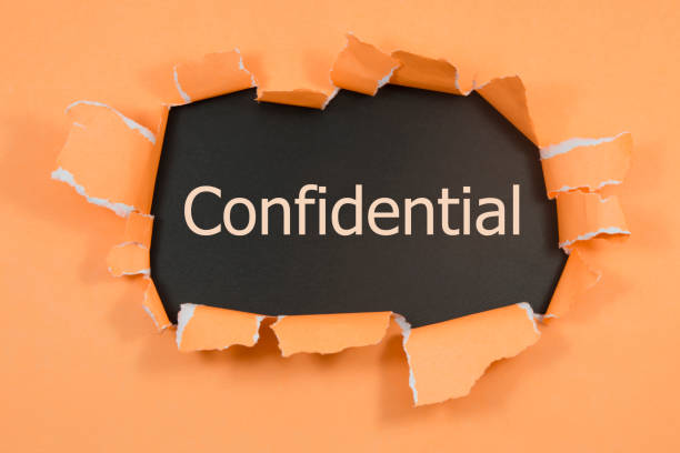 istock The word confidential appearing behind torn paper. 1018273600