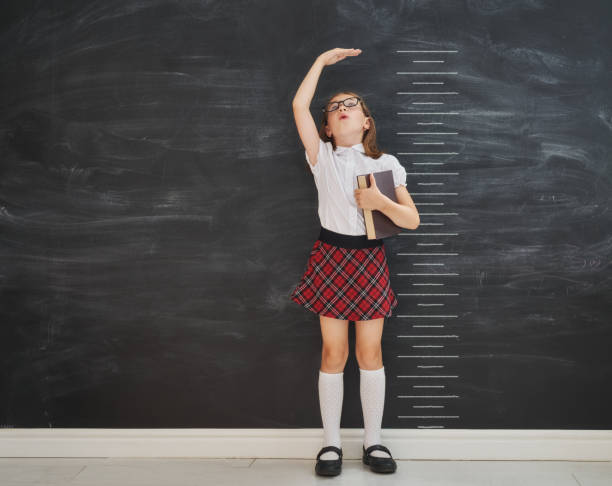 istock Kid measures growth on background of blackboard 1018282652