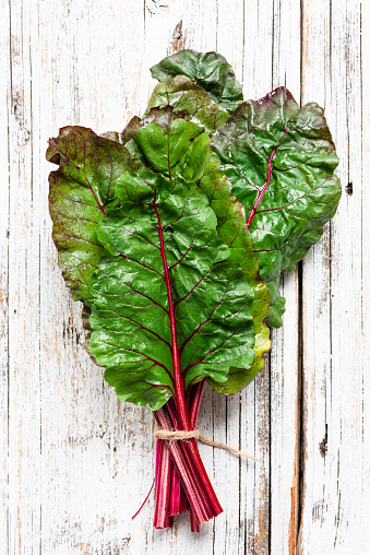 Swiss chard leaf on white wooden background. Top view. Organic green healthy food