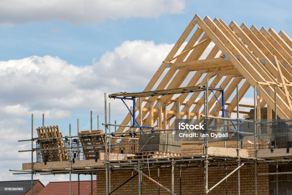 Industria de la construcción. Marco de madera de cerchas de techo de casa con andamios. - Foto de stock de Sector de la construcción libre de derechos