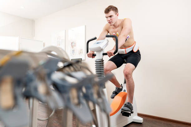 男性患者をチェック彼の心の関数の自転車エルゴ メーターによるストレス テスト システムのペダルします。選手は、医師によって監視されている医学研究で心臓のストレス テストを行いま - stethoscope human cardiovascular system pulse trace healthcare and medicine ストックフォトと画像