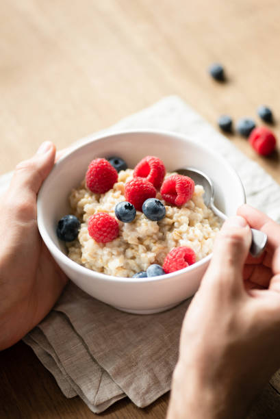 gachas de avena con moras en manos - oatmeal porridge oat raisin fotografías e imágenes de stock