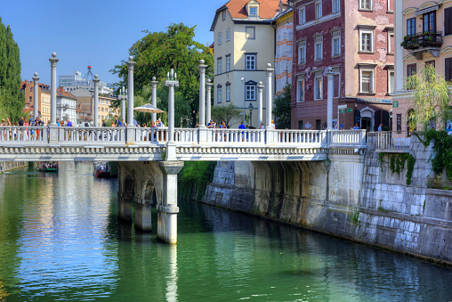 LJUBLJANA, SLOVENIA - AUGUST 10, 2018: The Cobblers' Bridge or the Shoemakers' Bridge is an arched pedestrian bridge crossing the river Ljubljanica in Ljubljana, the capital of Slovenia.  It connects two major areas of medieval Ljubljana.  It is one of the oldest bridges, dating back to the 13th century.  The current stone bridge was was designed in 1931 by the architect Joe Plenik