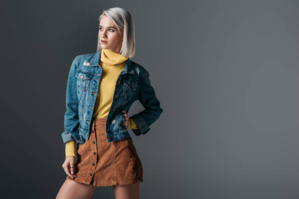 attractive woman posing in yellow turtleneck, trendy corduroy skirt and jeans jacket, isolated on grey attractive woman posing in yellow turtleneck, trendy corduroy skirt and jeans jacket, isolated on grey denim jacket stock pictures, royalty-free photos & images