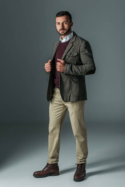 istock handsome male model posing in beige pants and tweed jacket, on grey 1018291256