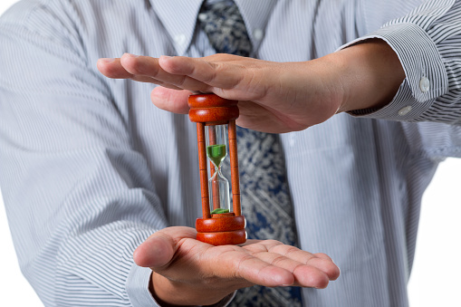 Close up of businessman holding hourglass between his hand