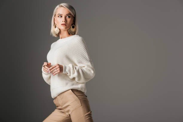 istock elegant blonde model posing in white knitted sweater, isolated on grey 1018293862