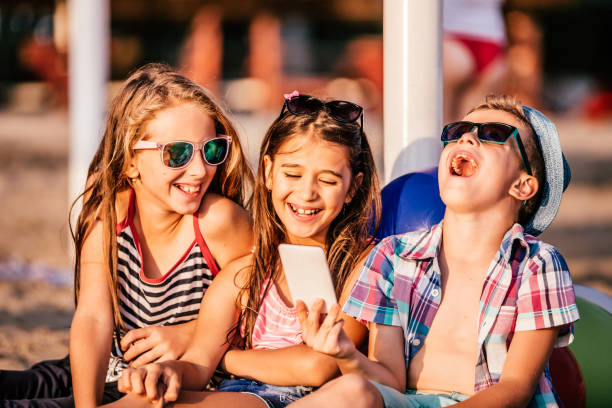istock Kids playing with mobile phones on sandy beach 1018299578