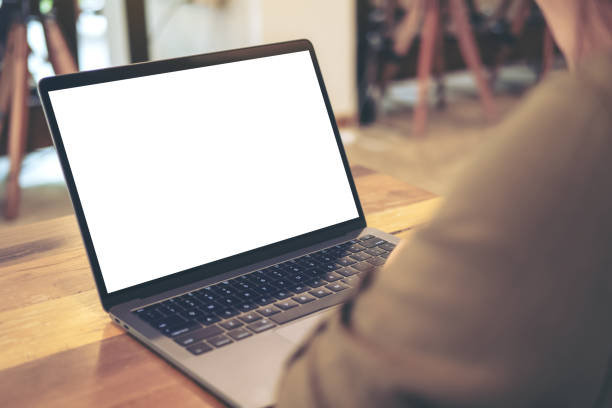 istock Mockup image of a woman using and looking at laptop with blank white screen on table in cafe 1018310918