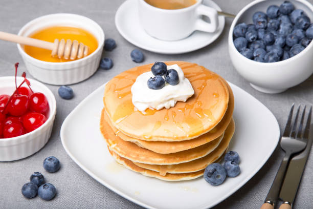 istock Pancakes with blueberries, cherries, sour cream, honey and coffee. 1018314318