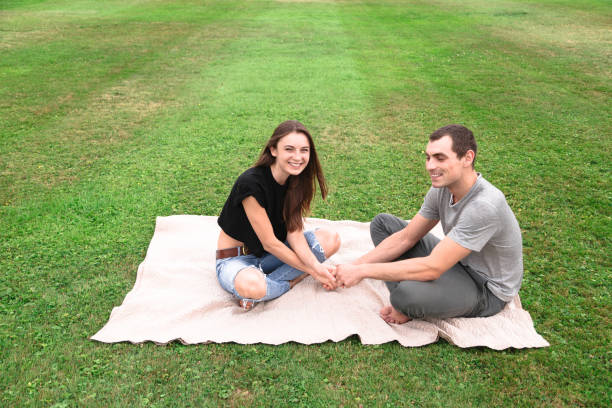 istock Young couple sit on a blanket on the grass 1018322738