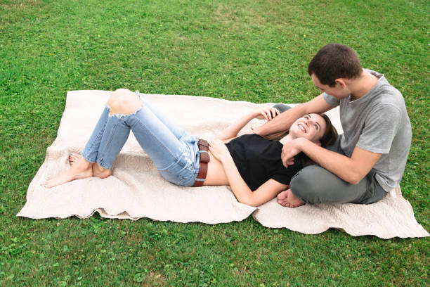 istock Young beautiful couple on blanket on grass 1018322744