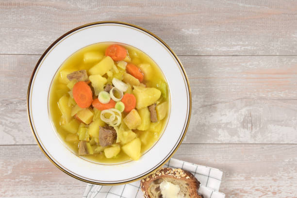 Traditional Welsh soup called Cawl made with a selection of root vegetables and meat, in this case lamb, served with bread and butter.