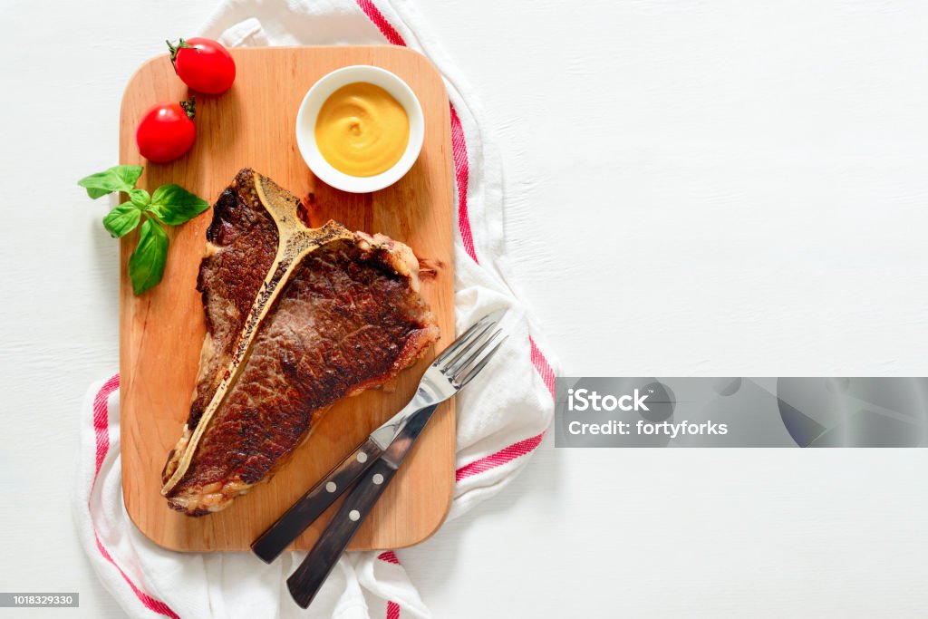 T-bone beef stake served on a cutting board T-bone beef stake served on a cutting board, view from above, space for a text Above Stock Photo