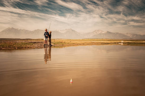 Two Young Boys Fishing On A Mountain Lake