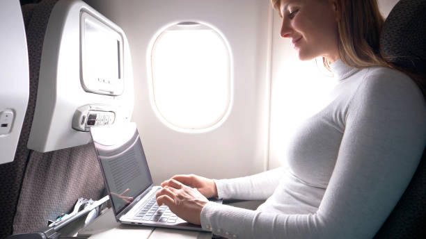 istock CLOSE UP: Happy businesswoman is typing on her high tech laptop during flight. 1018346764