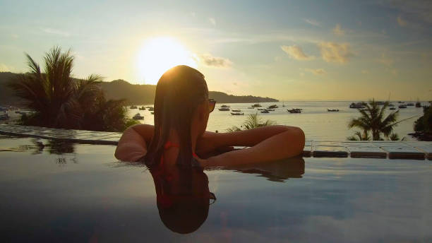 istock CLOSE UP: Girl stands in empty oceanfront infinity pool and looks at the beach. 1018346830