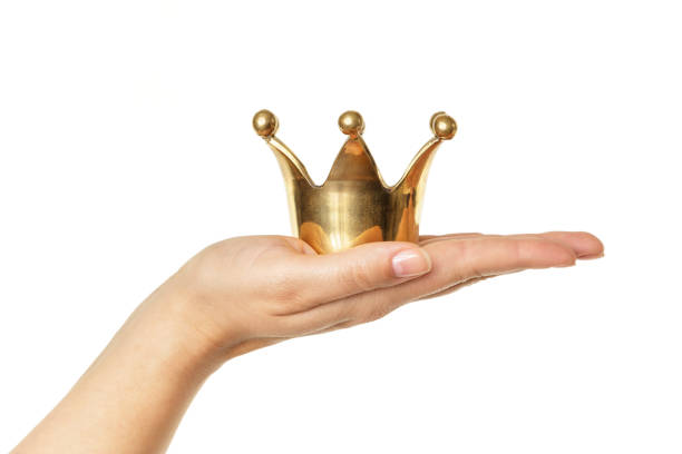 Female hand holding golden crown isolated on white background Female hand holding golden crown isolated on white background. Concept for success. coronation photos stock pictures, royalty-free photos & images