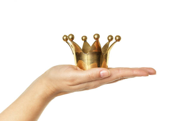 istock Female hand holding golden crown isolated on white background 1018347704