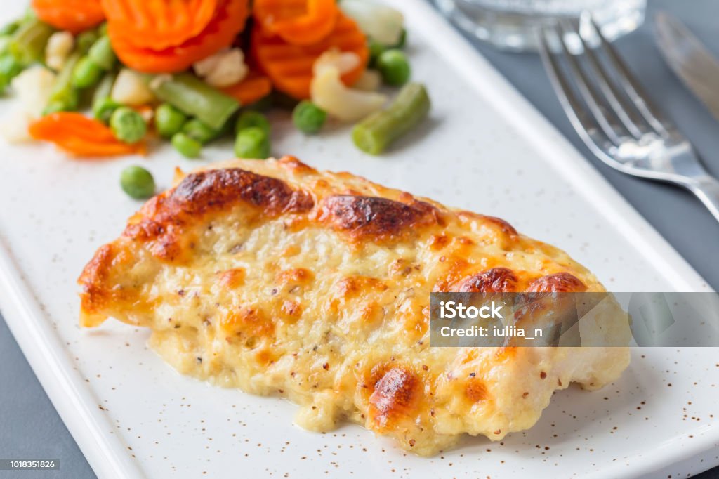 Baked cod fish fillet under cheese, mustard, pepper and cream crust, served with steamed vegetables, horizontal Baked cod fish fillet under cheese, mustard, pepper and cream crust, served with steamed vegetables, on a ceramic board, horizontal Cod Stock Photo