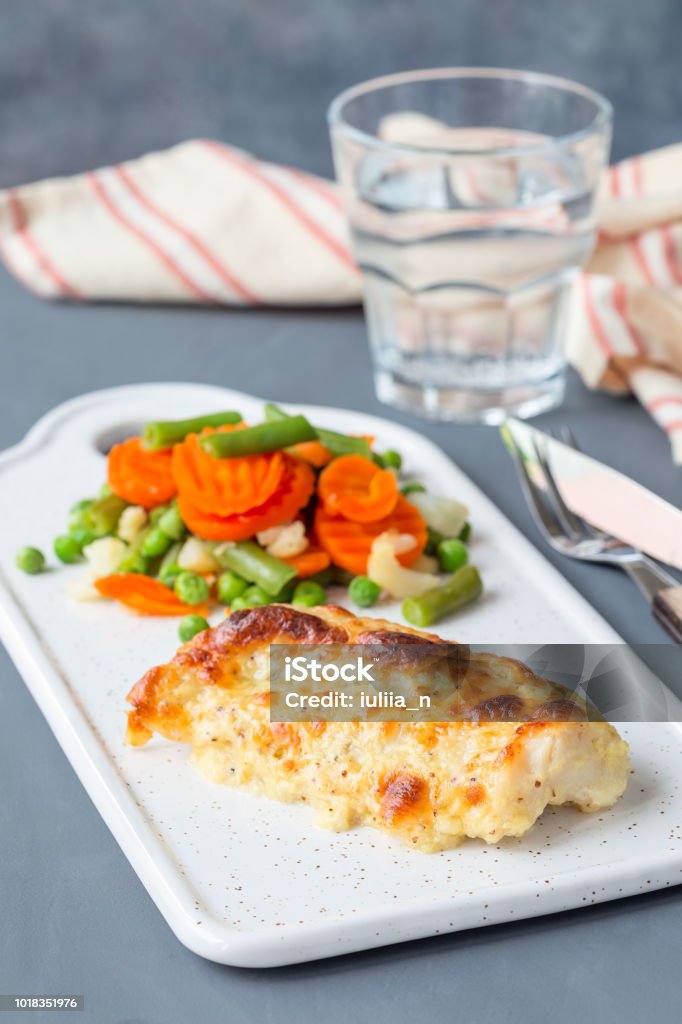 Baked cod fish fillet under cheese, mustard, pepper and cream crust, served with steamed vegetables, vertical Baked cod fish fillet under cheese, mustard, pepper and cream crust, served with steamed vegetables, on a ceramic board, vertical Acid Stock Photo