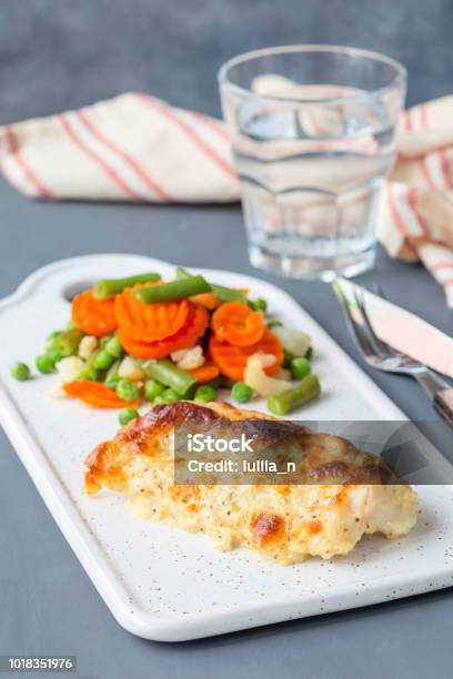 Baked Cod Fish Fillet Under Cheese Mustard Pepper And Cream Crust Served With Steamed Vegetables Vertical Stock Photo - Download Image Now
