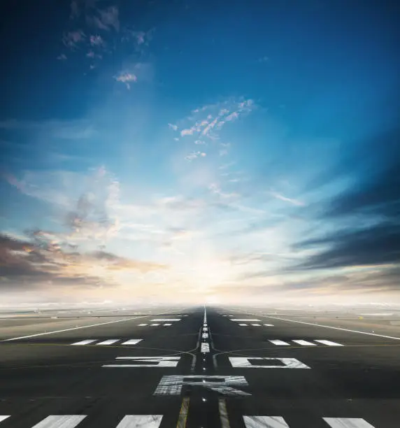 Empty asphalt airport runway with dramatic sky.