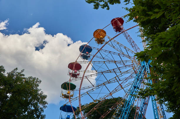istock Amusement park ferris wheel, blue sky with clouds, green trees 1018359408