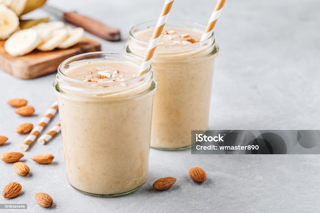 Banana almond smoothie with cinnamon and oat flakes and coconut milk in glass jars Healthy breakfast. Banana almond smoothie with cinnamon and oat flakes and coconut milk in glass jars Smoothie Stock Photo